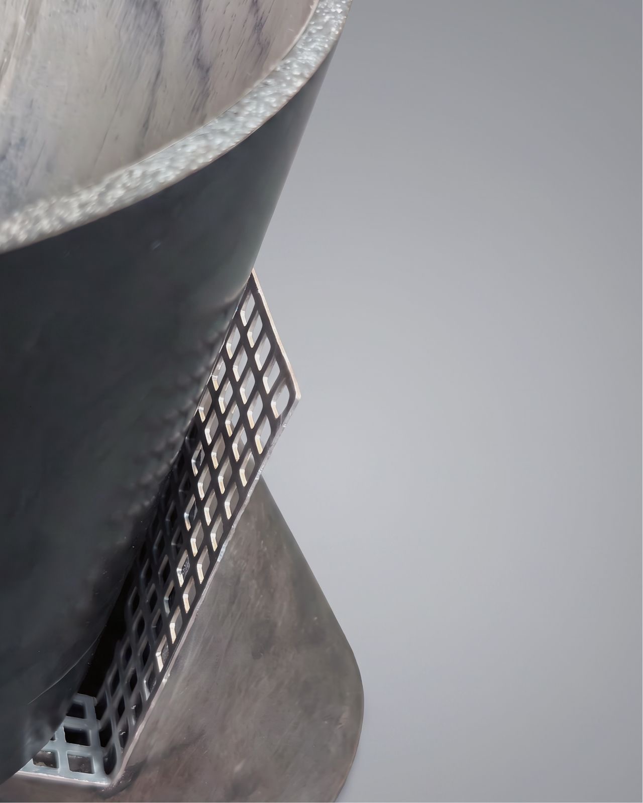 Détail : intérieur en pierre veinée contre grille métallique perforée — contraste de textures.