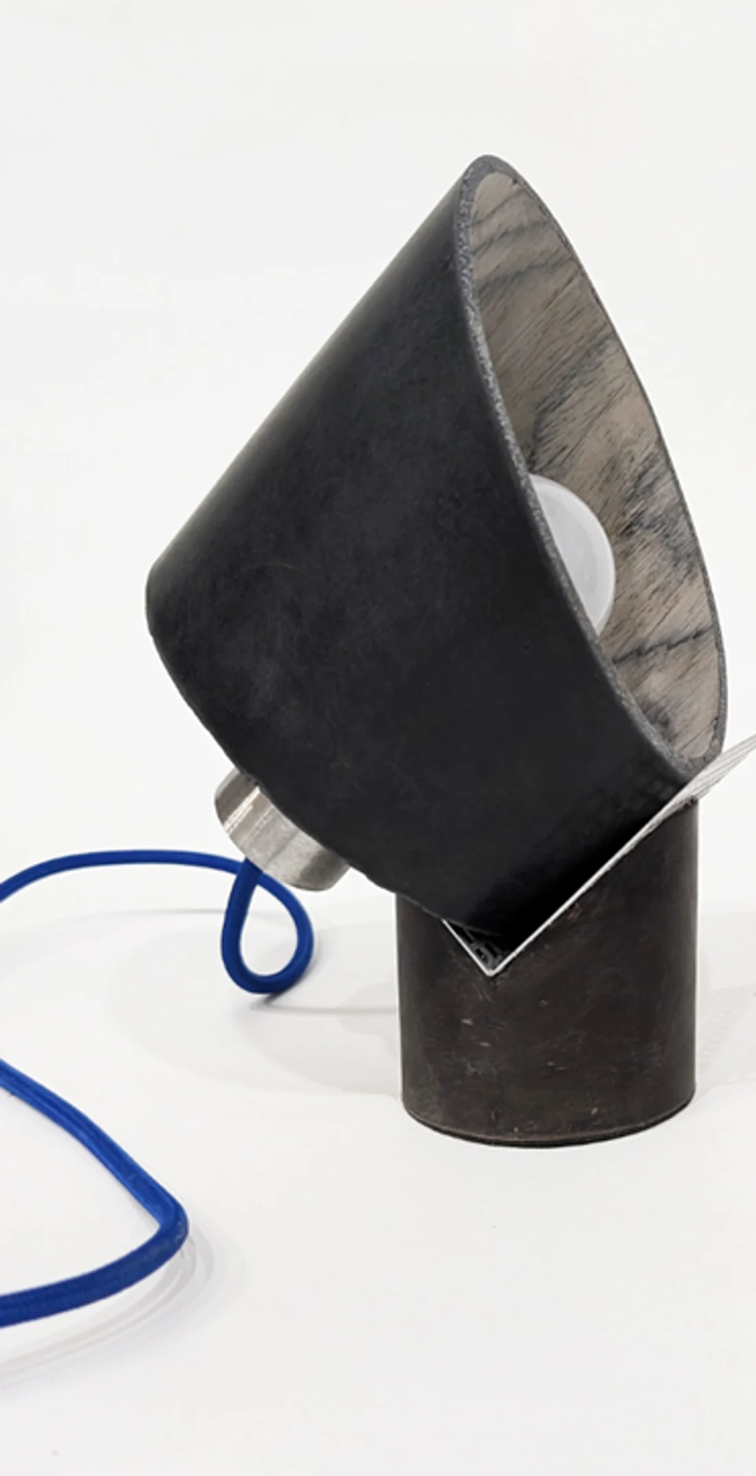 Prototype de la lampe Noir Minéral : abat-jour noir mat à l'intérieur clair en bois, pied sombre, assemblage métallique et câble textile bleu.